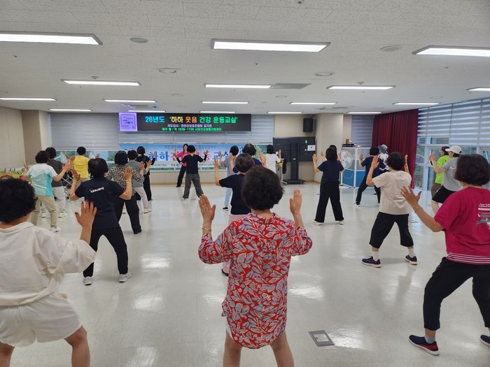 Seniors at the Seochang Health Life Support Center (서창건강생활지원센터) participate in the 'Ha-ha Laughter Wellness Exercise Class,' performing group calisthenics together.
