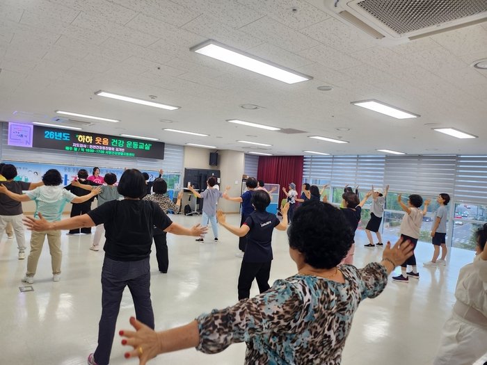 An instructor from the Incheon Health Promotion Association (인천건강증진협회) leads a laughter therapy session for senior participants.
