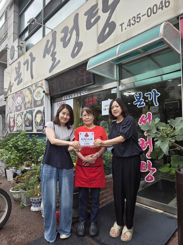 Miembros del Comité Autónomo de Jefes de Manzana de Namchon-dorim-dong (남촌도림동 통장자율회) reparan un sumidero bajo la lluvia.